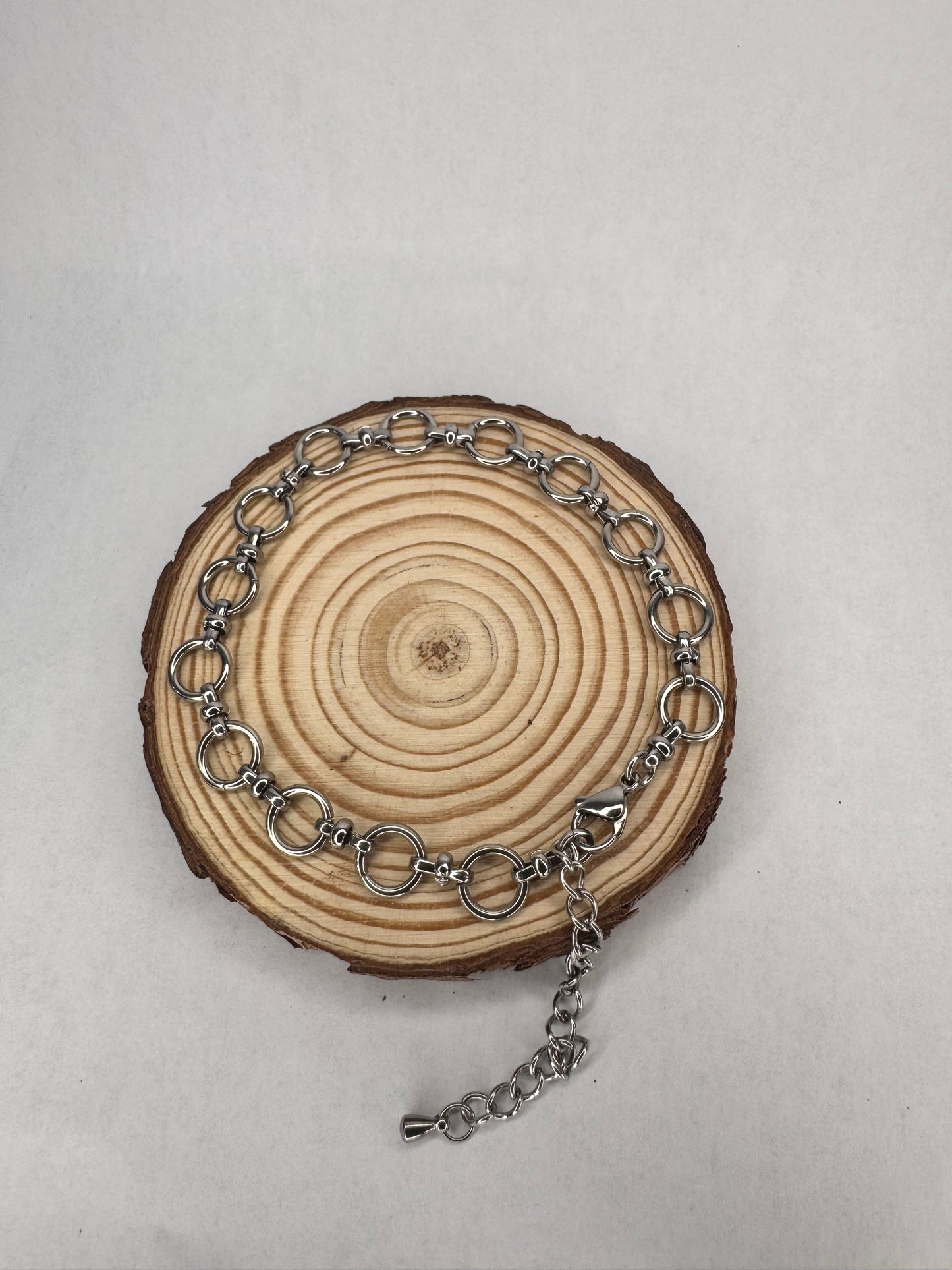 Silver chain anklet on a wooden circular piece with a light gray background
