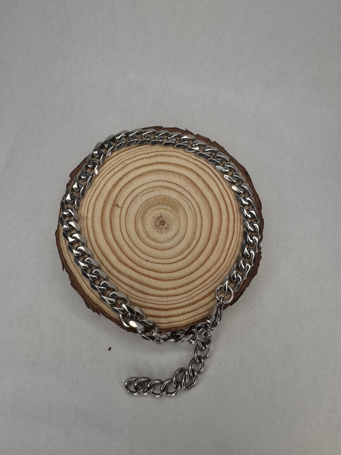 Wooden disc with silver anklet on a gray background