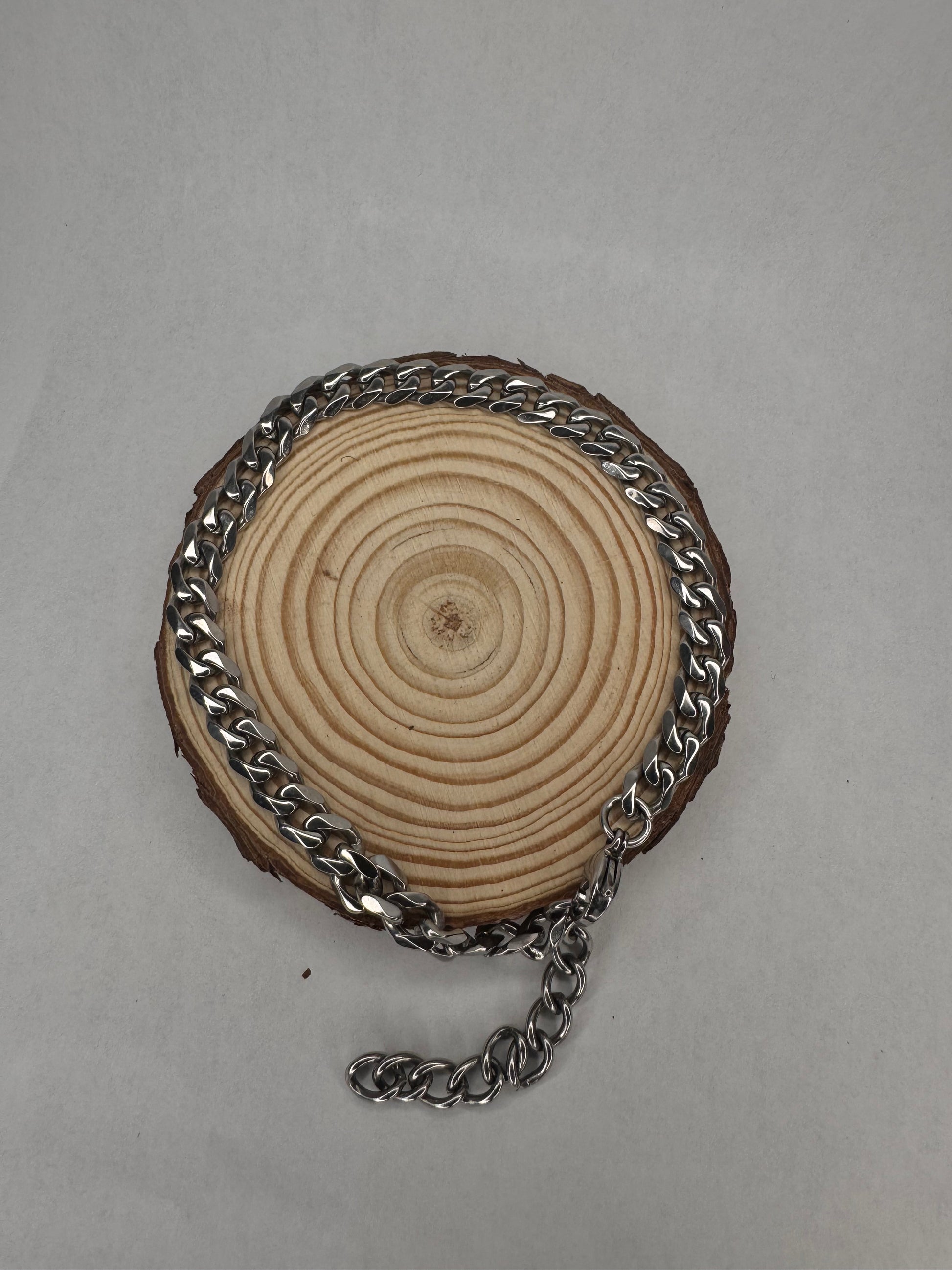 Wooden disc with silver anklet on a gray background