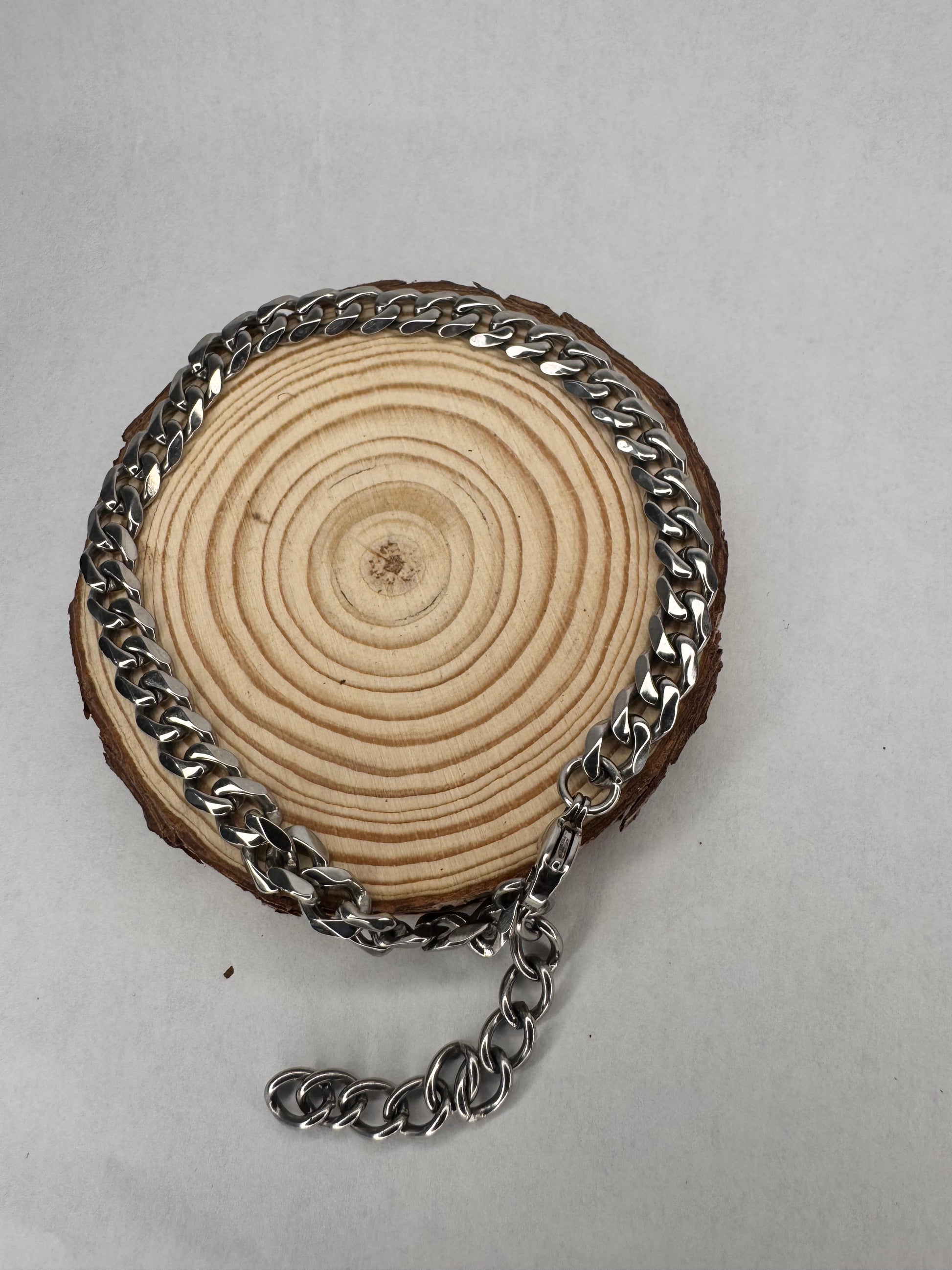 Wooden circular object with a silver anklet  on a gray background