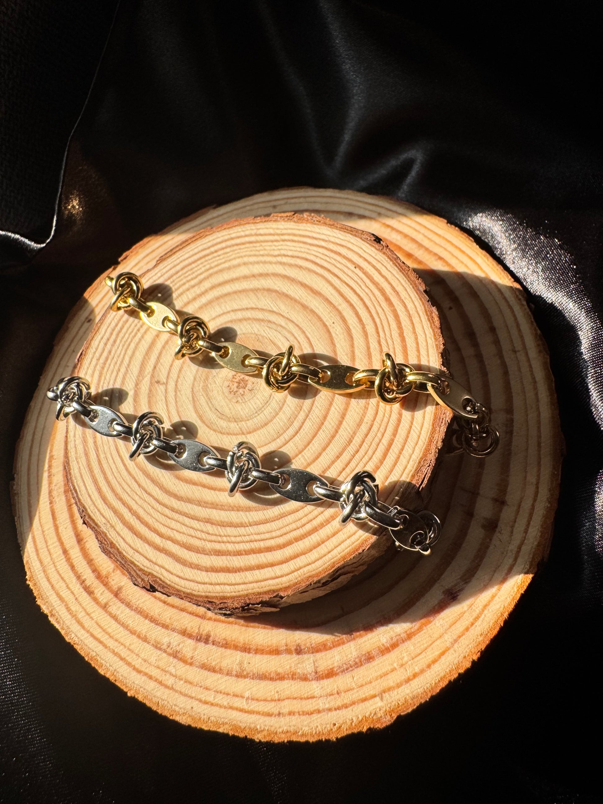 Gold and silver chain anklets on a wooden surface