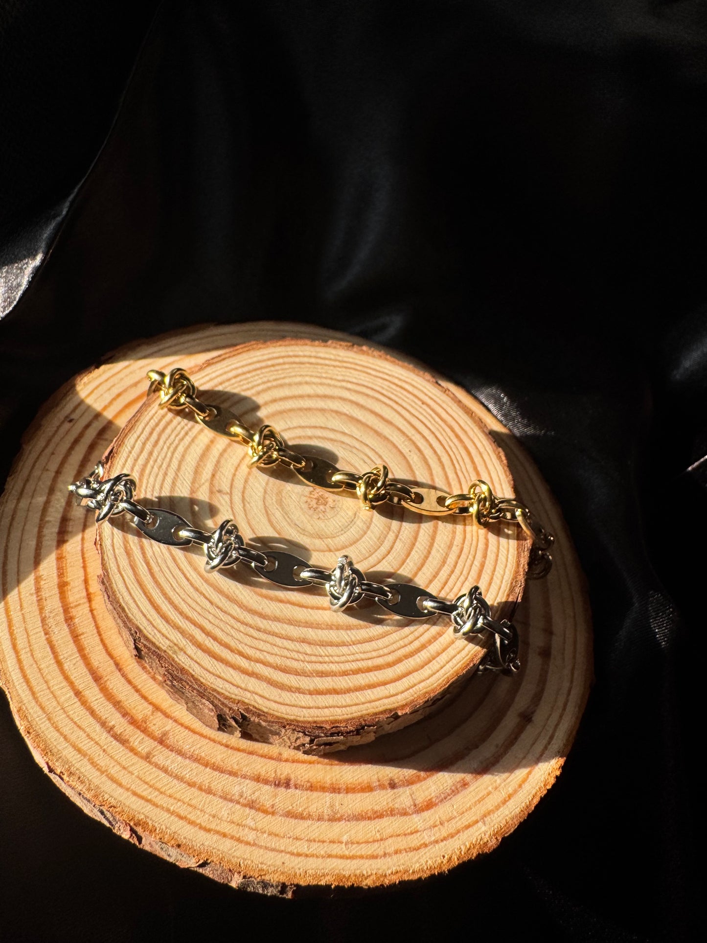 Pair of gold and silver anklets on a wooden surface