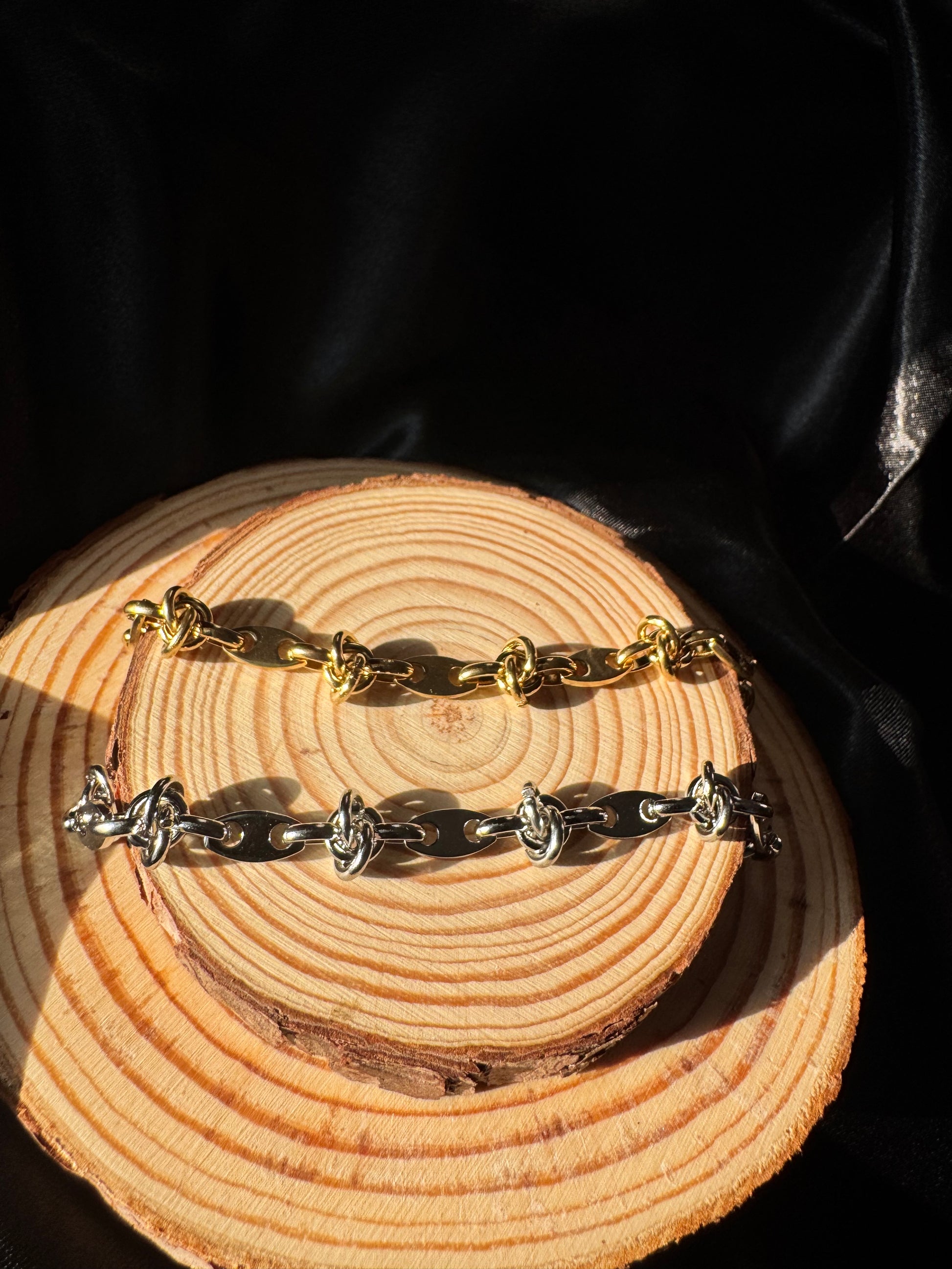 Gold and silver chain anklets on a wooden surface