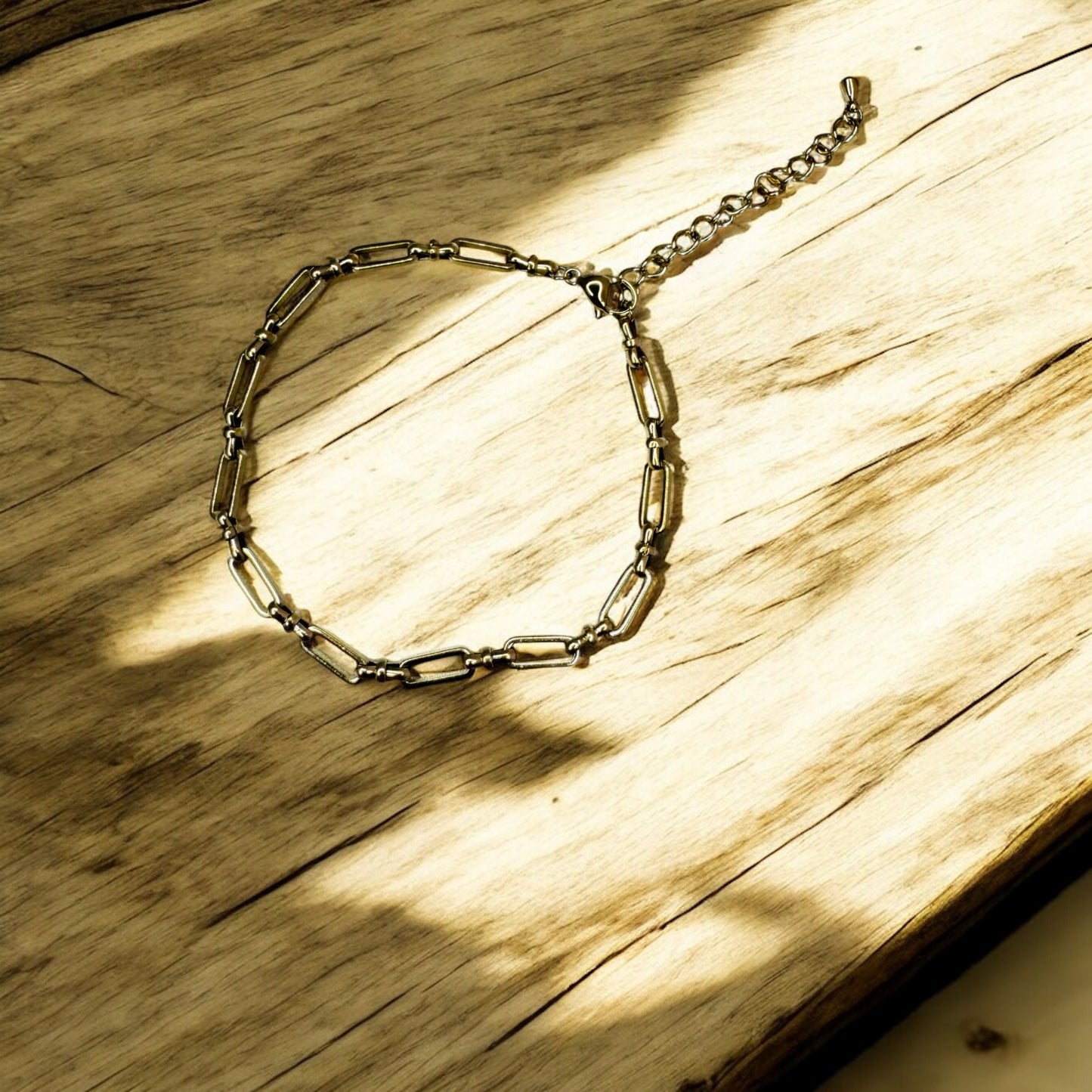 Metallic bold link anklet on a wooden surface