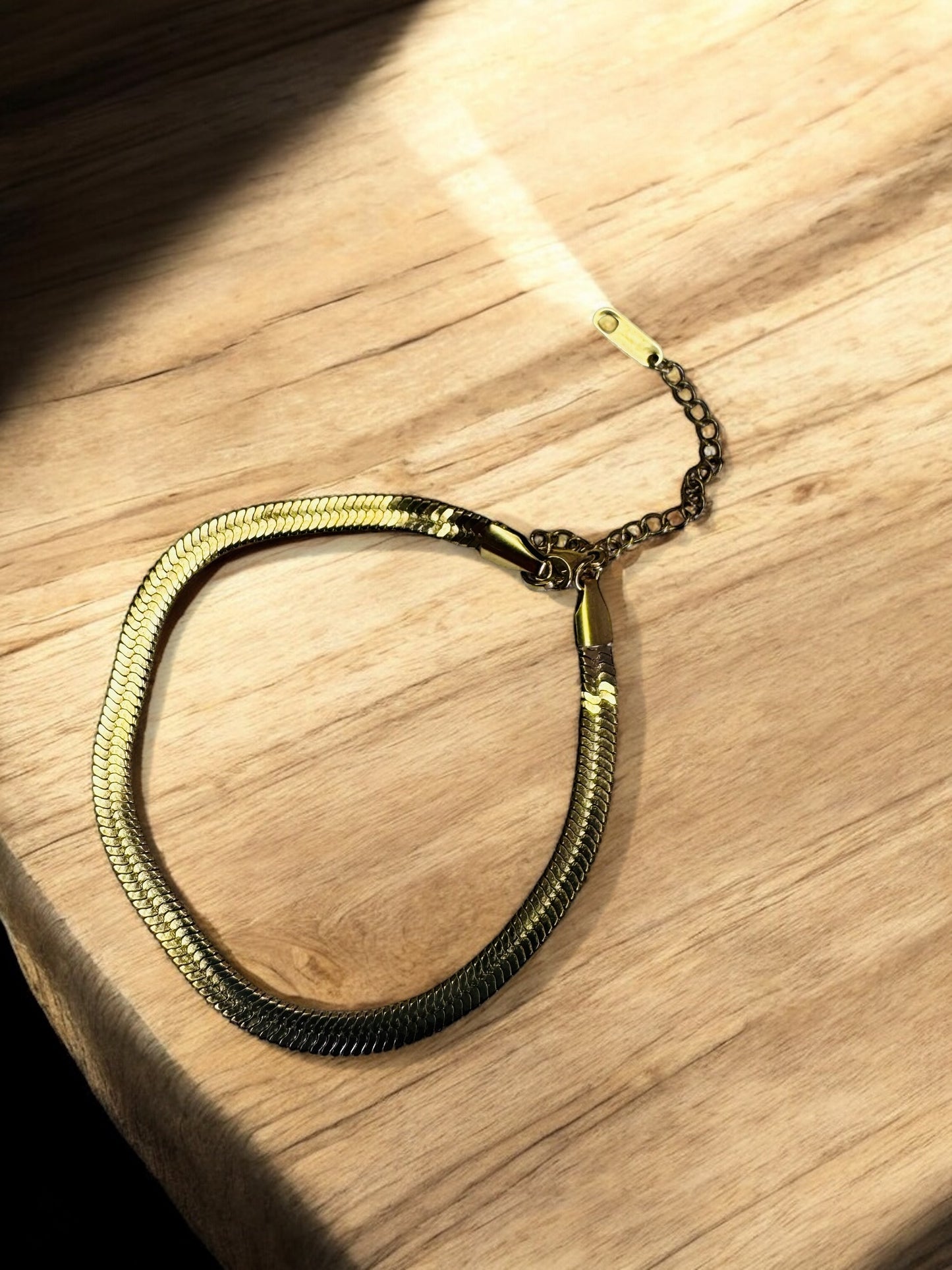 Gold and black braided bracelet on a wooden surface