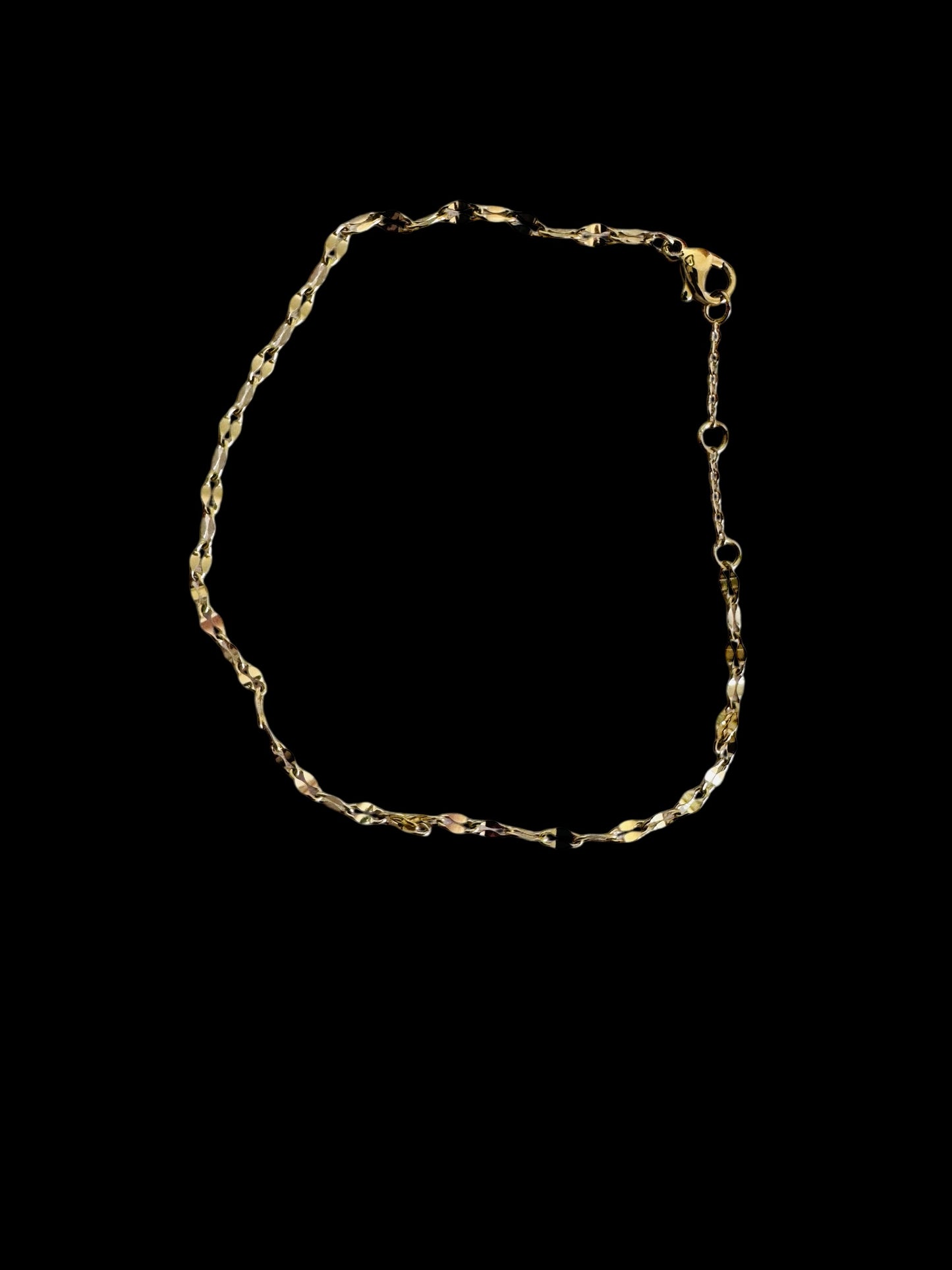 Gold twinkle anklet on a black background