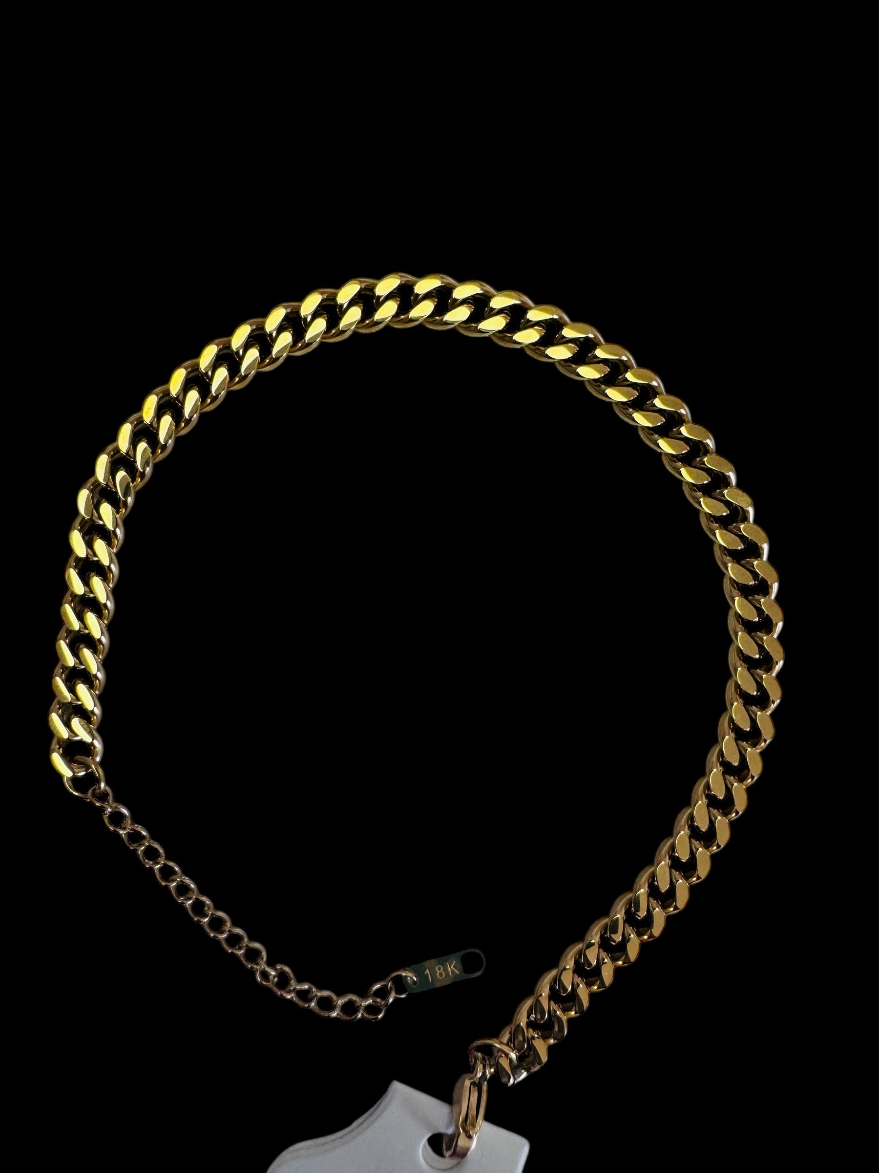 18k cuban link anklet with a tag on a black background