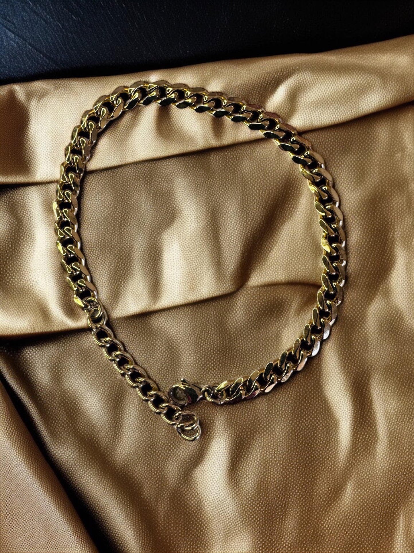 Gold chain anklet on a beige-gold fabric background