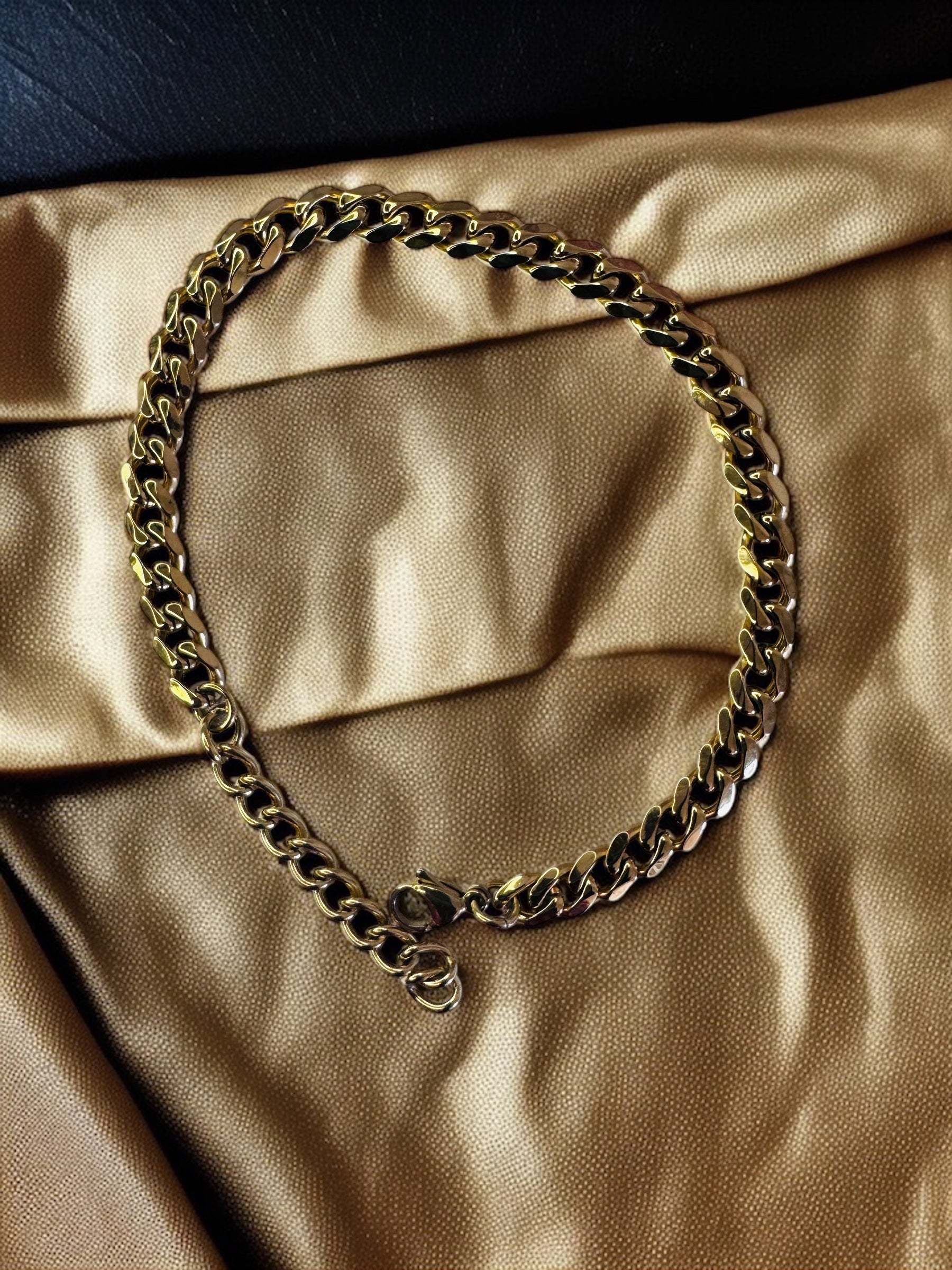 Gold chain anklet on a beige-gold fabric background