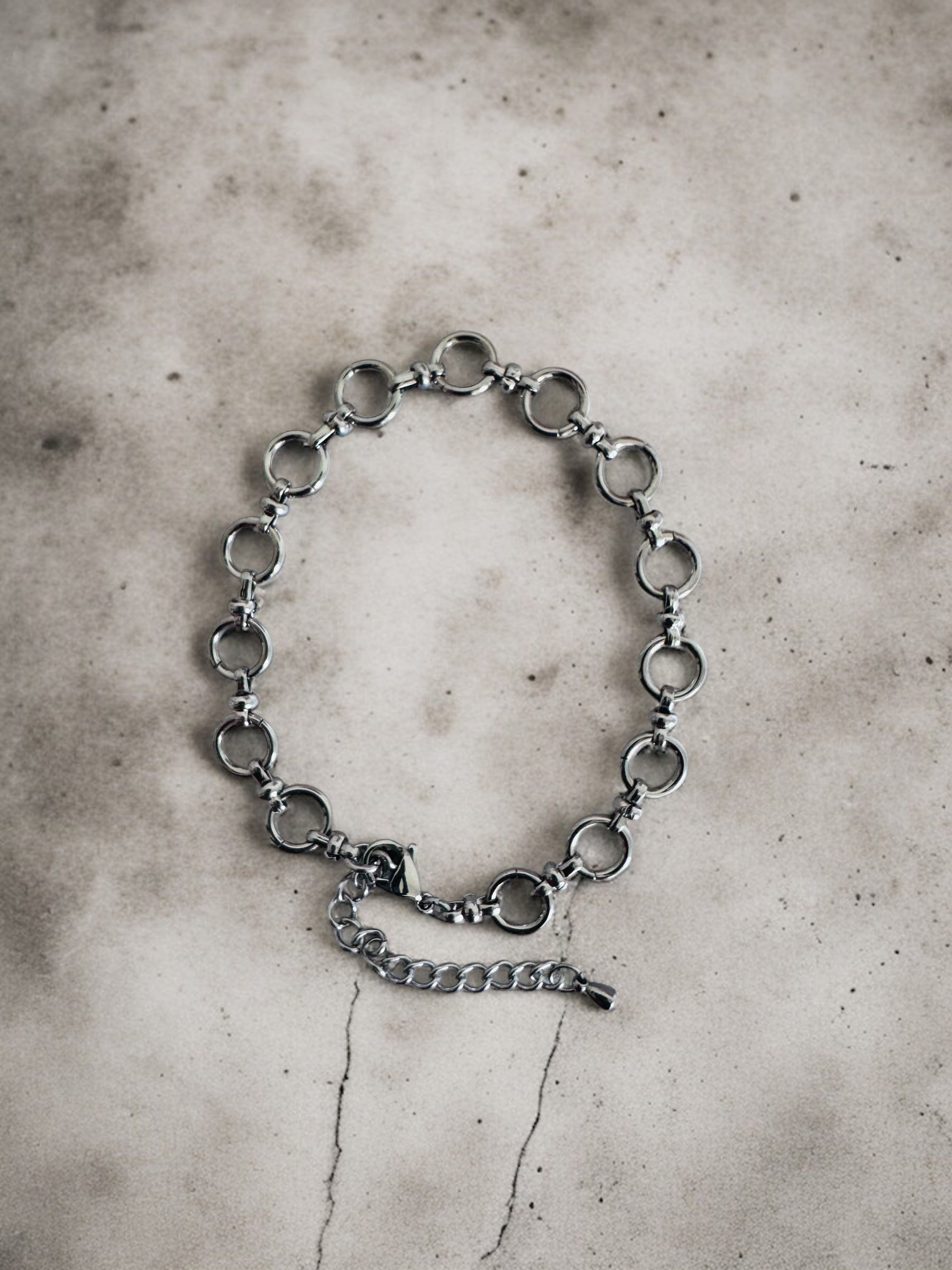 Silver chain anklet on a textured gray surface